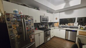 A modern kitchen with white cabinets, stainless steel appliances, and wooden flooring. - Unique One Bedroom with VIP Terrace in Yonge & Eglinton and 5 minutes to Subway (Toronto)