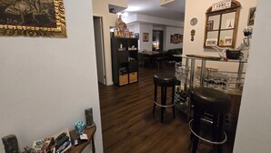 A room with a wooden floor, a dining area with a table and chairs, a bar area with stools and a glass display, and a wall with a framed picture and a mirror. - Unique One Bedroom with VIP Terrace in Yonge & Eglinton and 5 minutes to Subway (Toronto)