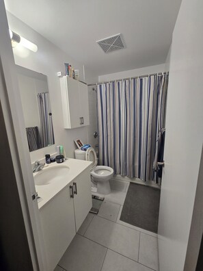 Un bagno con lavandino bianco, WC e tenda da doccia a righe.