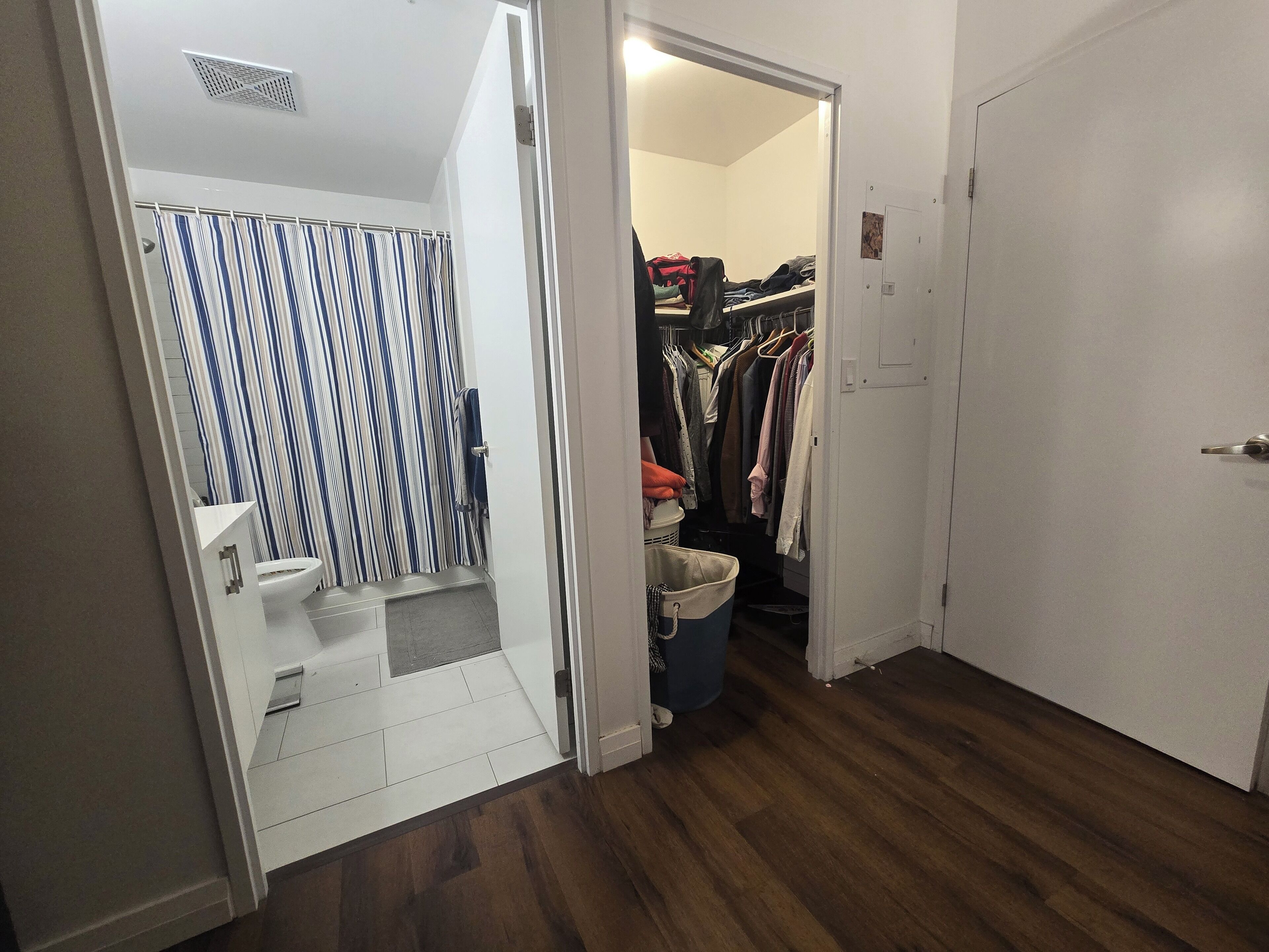 A bathroom with a striped shower curtain, a toilet, and a small sink.