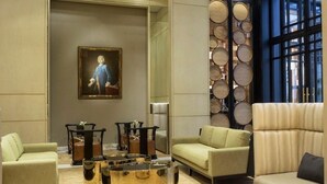 Una sala de estar moderna con chimenea, asientos cómodos, un cuadro grande y un muro decorativo.