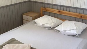 A neatly made bed with white linens and two pillows, a wooden headboard, and a small bedside table with a drawer. - Cozy chalet with terrace - 5 guests (Les Mages)