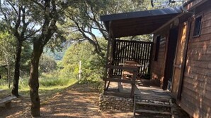 A wooden cabin with a porch, white plastic chairs, and a stone pathway. - Cozy chalet with terrace - 5 guests (Les Mages)