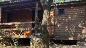A rustic wooden cabin with a stone foundation, a wooden porch, and a small window. - Cozy chalet with terrace - 5 guests (Les Mages)