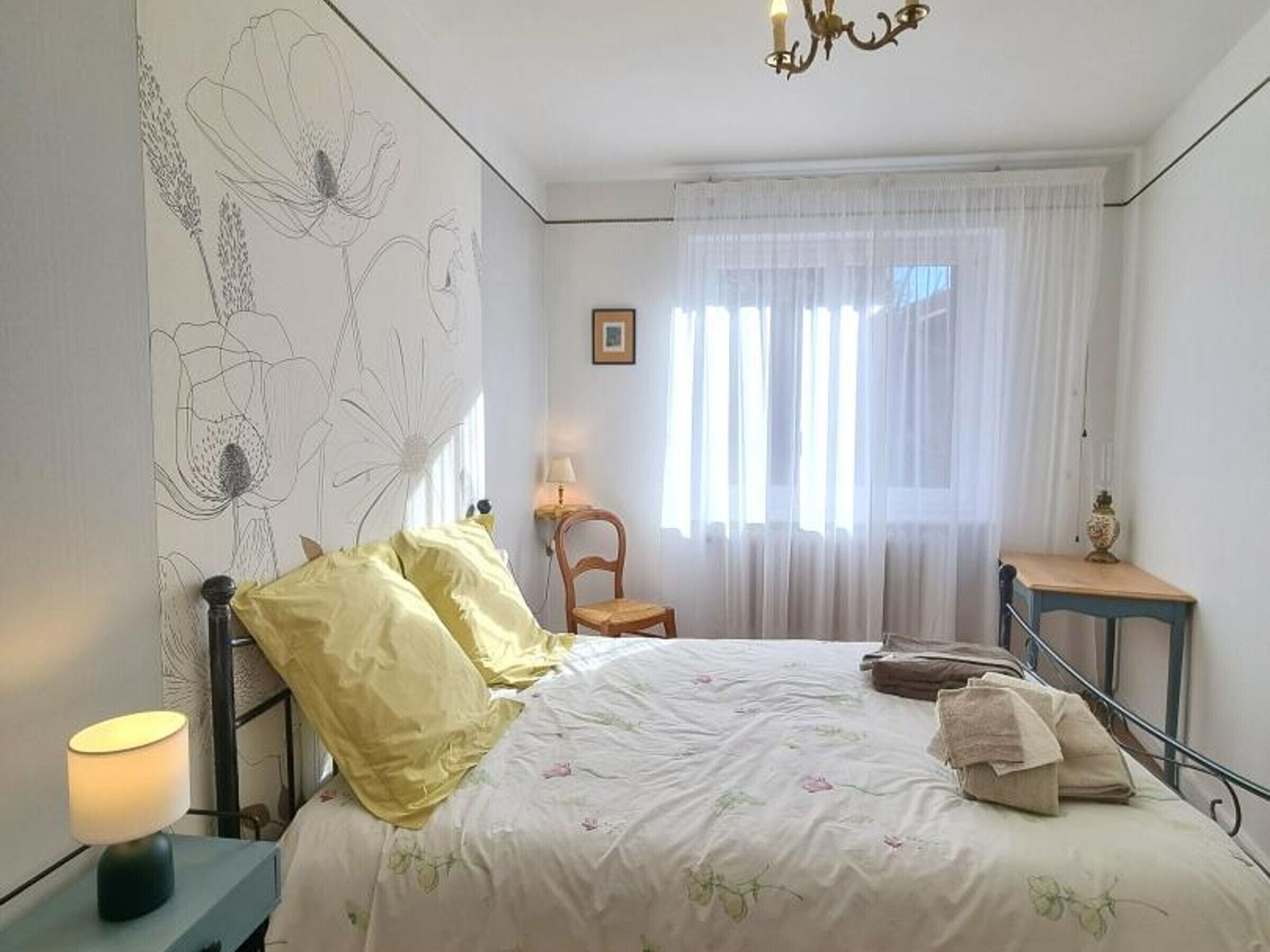 Una camera da letto con un letto, un comodino, una sedia, un tavolo e un lampadario.