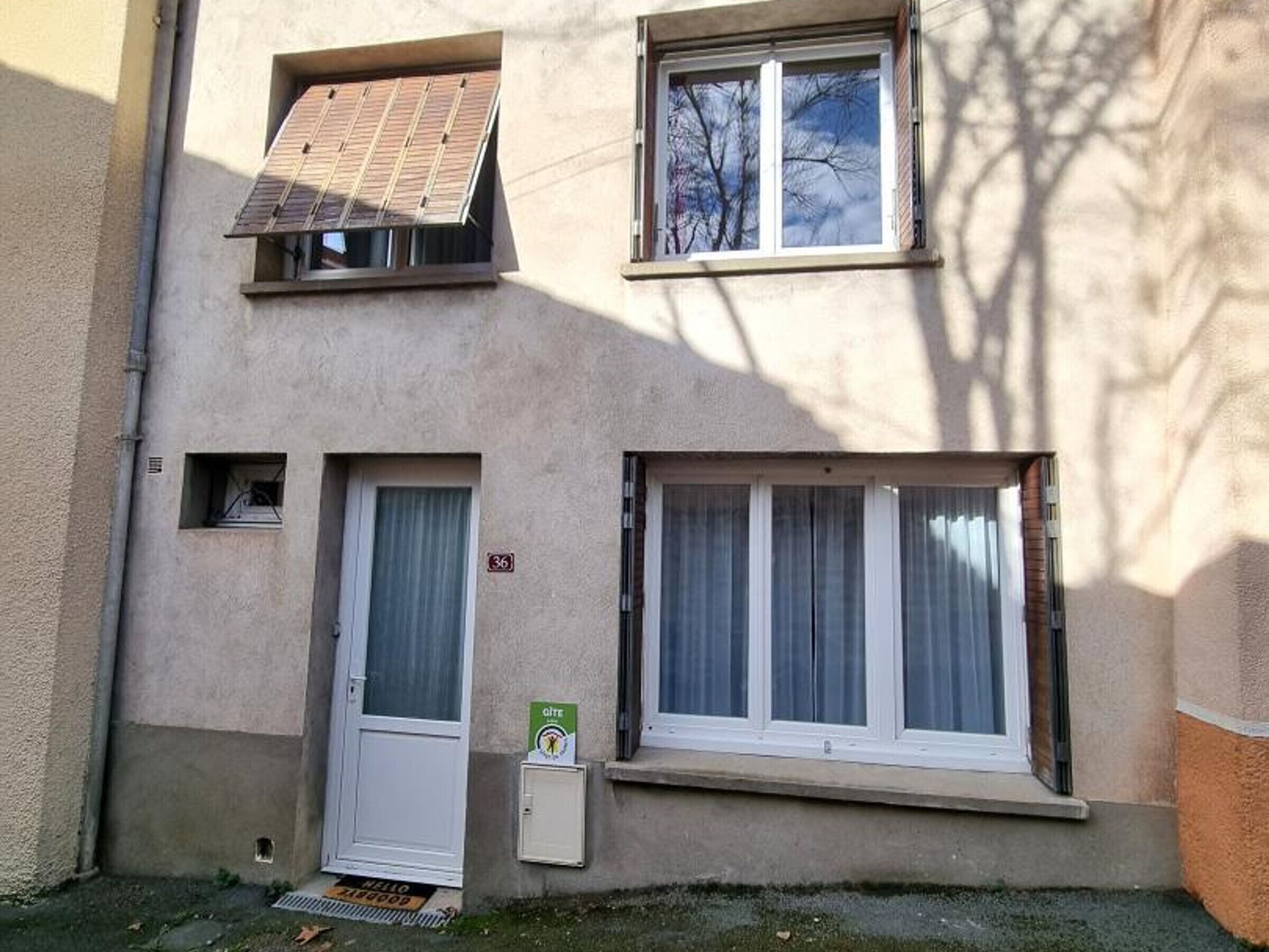 A two-story building with a door, a window with curtains, and a solar panel on the roof.