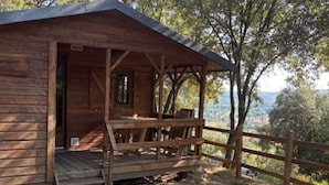 Una cabaña de madera con un porche y vistas del paisaje circundante.