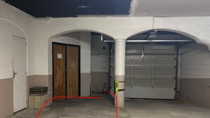 Uma área interna de estacionamento com uma porta de garagem fechada, uma porta de madeira e um piso de concreto.