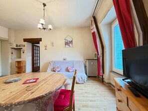 A cozy bedroom with a bed, a TV, a wooden dresser, and a dining table. - Mont-Dore - Central T3, WIFI, 100m to Amenities (Mont-Dore)