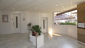 A clean, modern lobby with a marble floor, a staircase with metal railings, and a potted plant. - Apartment for 4, near beach - AC (Lloret de Mar)