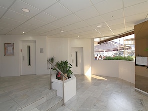 A clean, modern lobby with a marble floor, a staircase with metal railings, and a potted plant. - Apartment for 4, near beach - AC (Lloret de Mar)