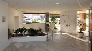 A clean, modern lobby with a tiled floor, a reception desk, and potted plants. - Apartment for 4, near beach - AC (Lloret de Mar)