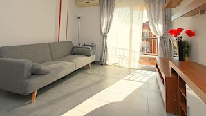 A modern living room with a grey sofa, a standing lamp, and a wooden sideboard. - Apartment for 4, near beach - AC (Lloret de Mar)