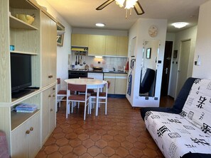 A compact living space with a dining area, kitchenette, and a sofa. - 2-room apartment with air conditioning, sea view in Bormes-les-Mimosas (Bormes-les-Mimosas)