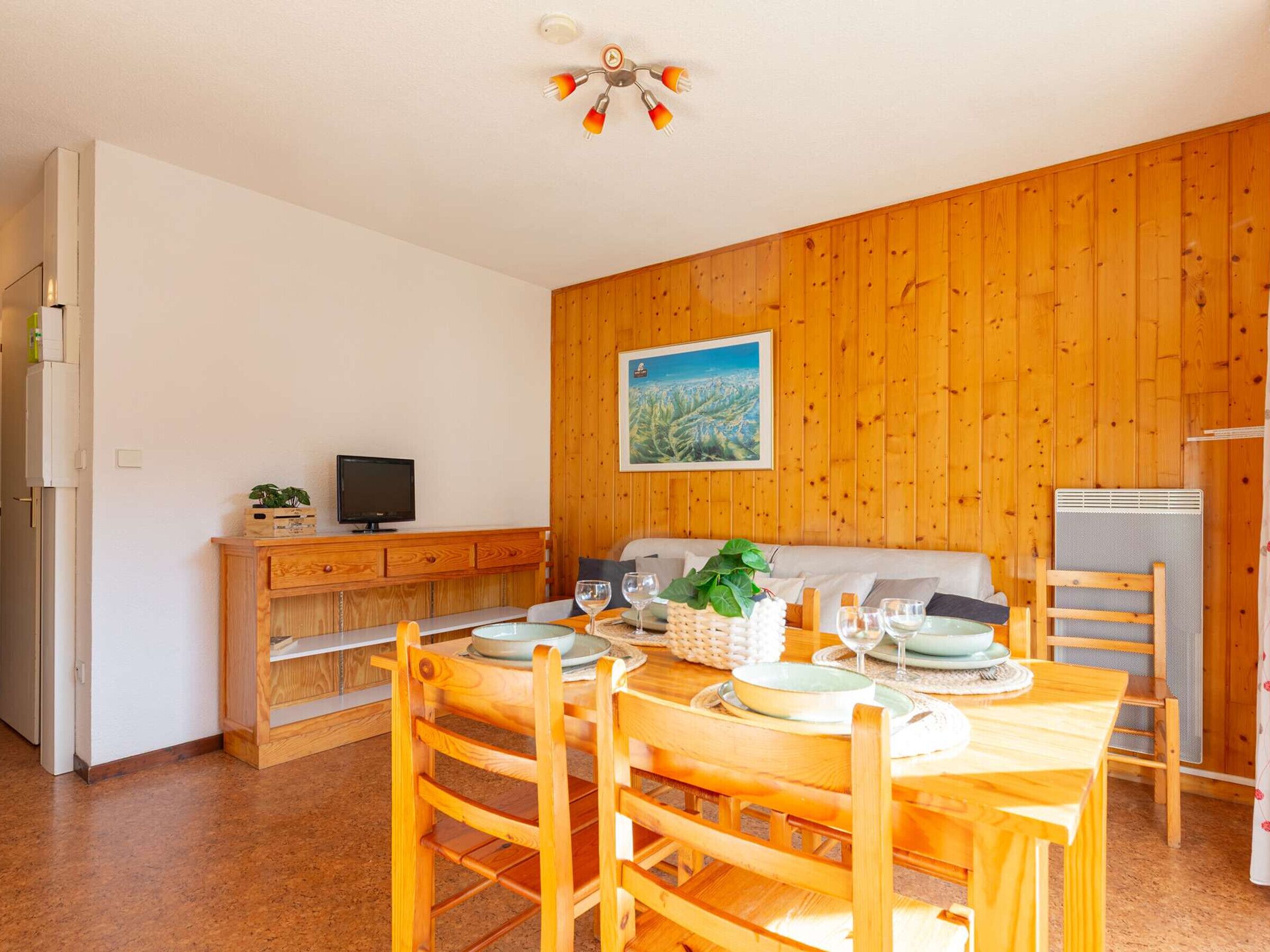 A dining area with wooden furniture, a television on a cabinet, and a painting on the wall.