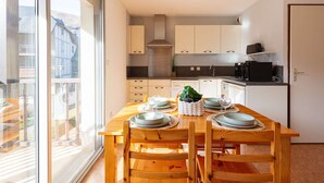 Una cucina moderna con mobili bianchi, un forno a microonde nero e un tavolo da pranzo per quattro persone con sedie in legno.