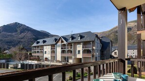Un hotel a più piani con balconi, un’area parcheggio e vista sulle montagne.