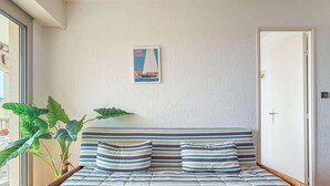 A room with a bed, a poster on the wall, and a plant. - Apartment with panoramic sea view - 4 guests (Bormes-les-Mimosas)
