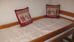 Un lit superposé avec un matelas et deux oreillers, l’un décoré d’un motif représentant un paysage de ski et l’autre représentant un skieur.