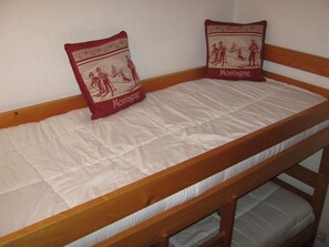 A bunk bed with a mattress and two pillows, one with a ski scene and the other with a skier. - Cozy studio for 4 people with parking in Châtel (Châtel)