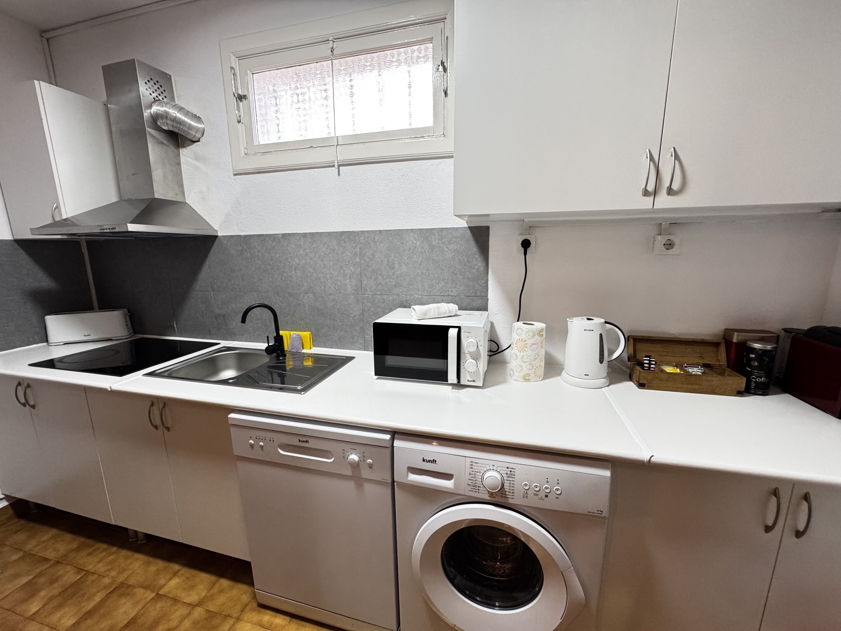 A compact kitchen with a dishwasher, microwave, and washing machine.