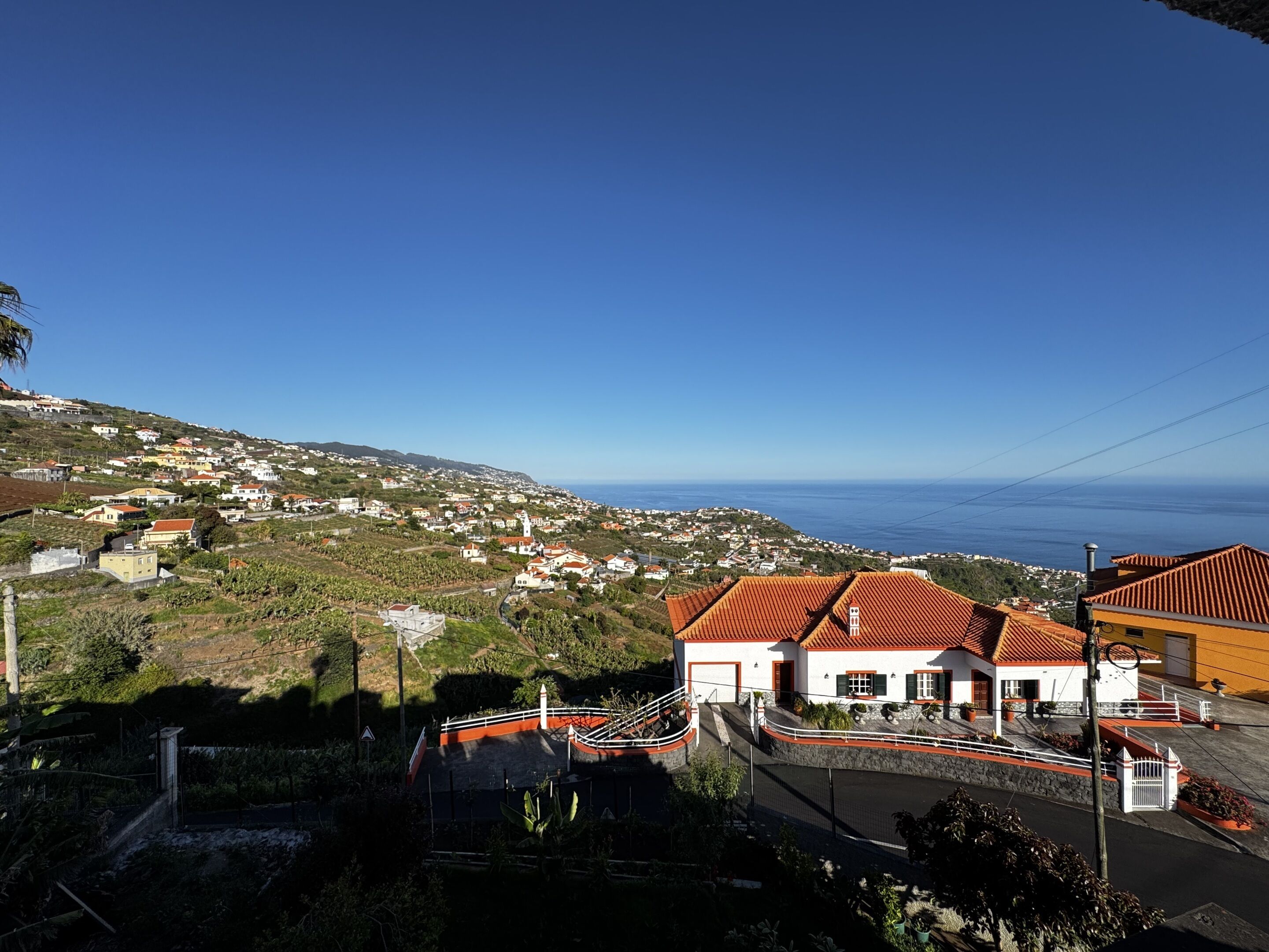 Une ville côtière avec des maisons, un ciel dégagé et la mer en arrière-plan.