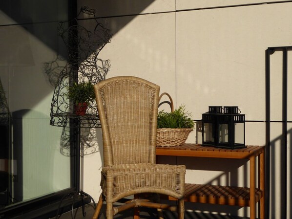 A wicker chair, a small table with a lantern, and a plant on a balcony. - Garden Room - Private bathroom and toilet. (Molenbeek-Saint-Jean)