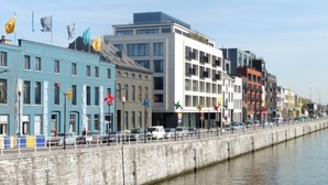 Een waterhek met moderne gebouwen, een stenen muur en een rustige rivier.