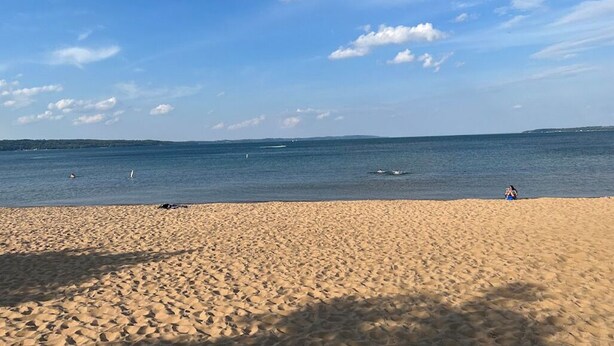 A beach with a clear sky and calm sea. - Summer Retreat in Traverse City: Steps to TART Trail & State Park Beach (Traverse City)