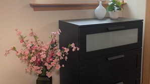 A room with a window, a black filing cabinet, a vase with pink flowers, and a potted plant on the window sill. - Southside 2-bedroom guest suite, ground level with private entrance (Anchorage)