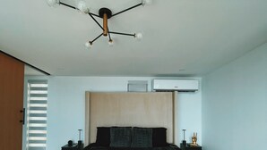 Una camera da letto moderna con un letto grande, un lampadario, un condizionatore d'aria e una finestra con persiane.