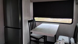 Eine kleine Küchenzeile mit Kühlschrank, Tisch und Stuhl.
