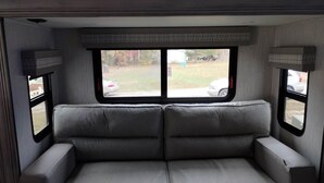 Ein Zweisitzer-Sofa in einem Wohnwagen mit zwei Fenstern, eines davon mit einem 'EXIT'-Schild.