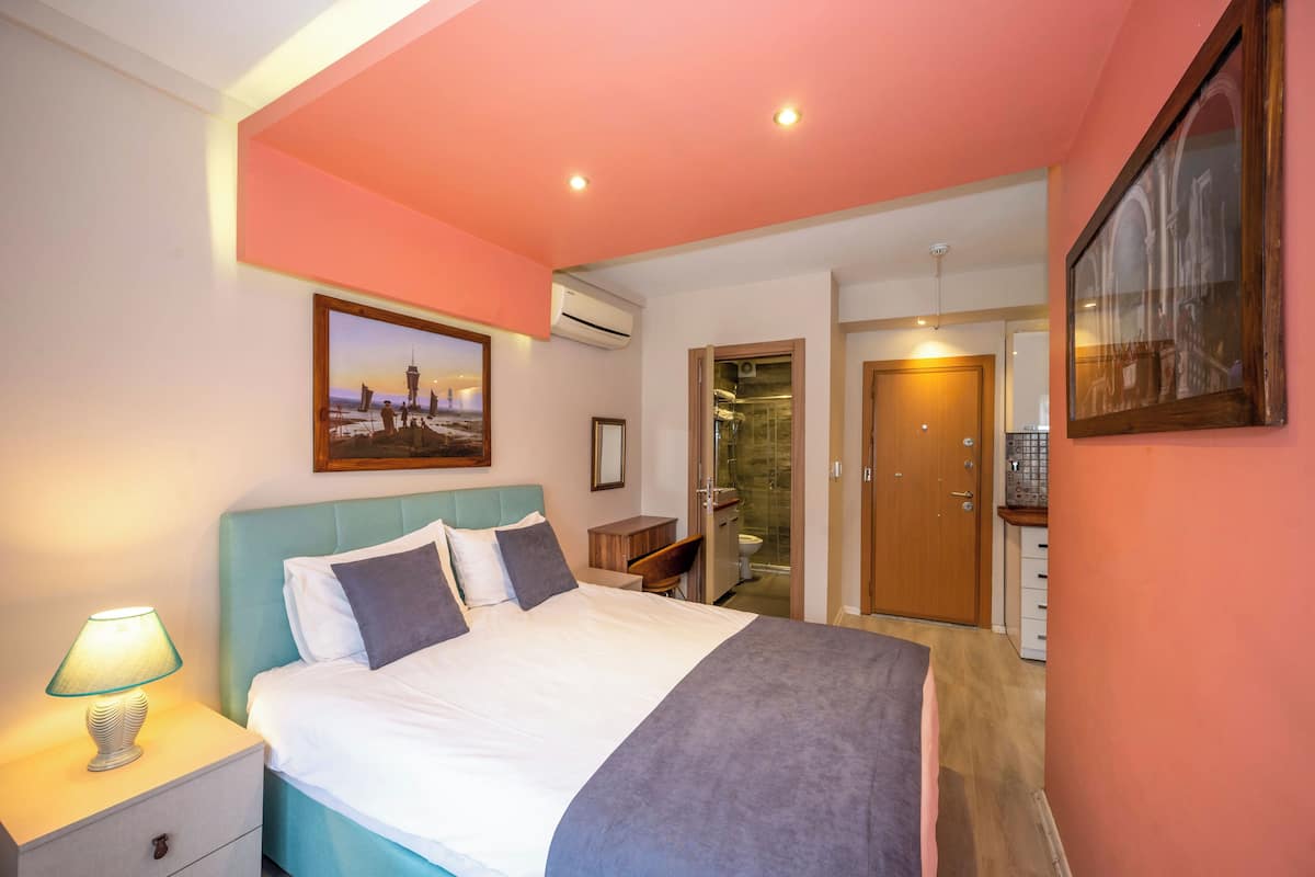 A bedroom with a bed, nightstand, and a picture of a cityscape.