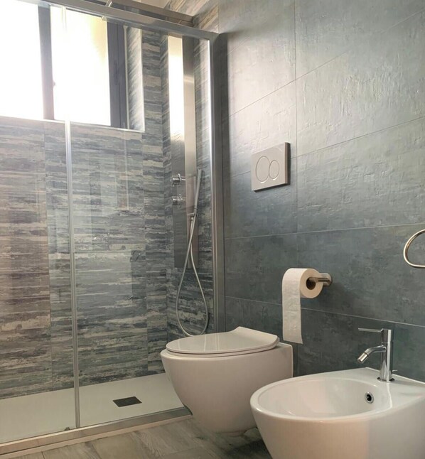 Een badkamer met een douchecabine van glas, een toilet en een wastafel.