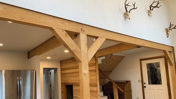 Un vaste espace de vie doté d’un plafond en bois, d’un escalier et d’une porte avec une fenêtre.