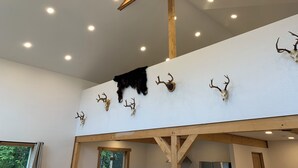 Une pièce avec un plafond en pente, des poutres en bois et un ventilateur de plafond.