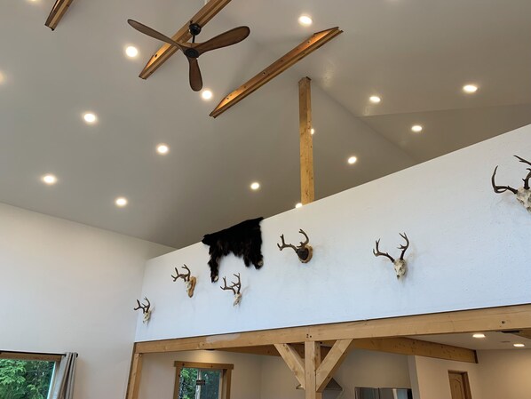 A room with a sloped ceiling, wooden beams, and a ceiling fan.