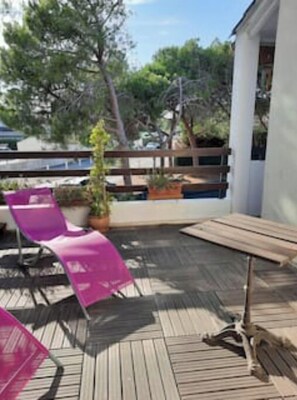 Una terrassa de fusta amb taula i cadires, barana i plantes en testos.