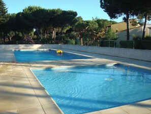 Una piscina amb un solàrium emblumat i una persona en un flotsam groc.
