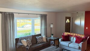 A living room with two sofas, a coffee table, a lamp, and a view of the street. - Sleeps 10 - 5BR - Minutes to Campus - Next to Park, Golf, Shopping (Ames)