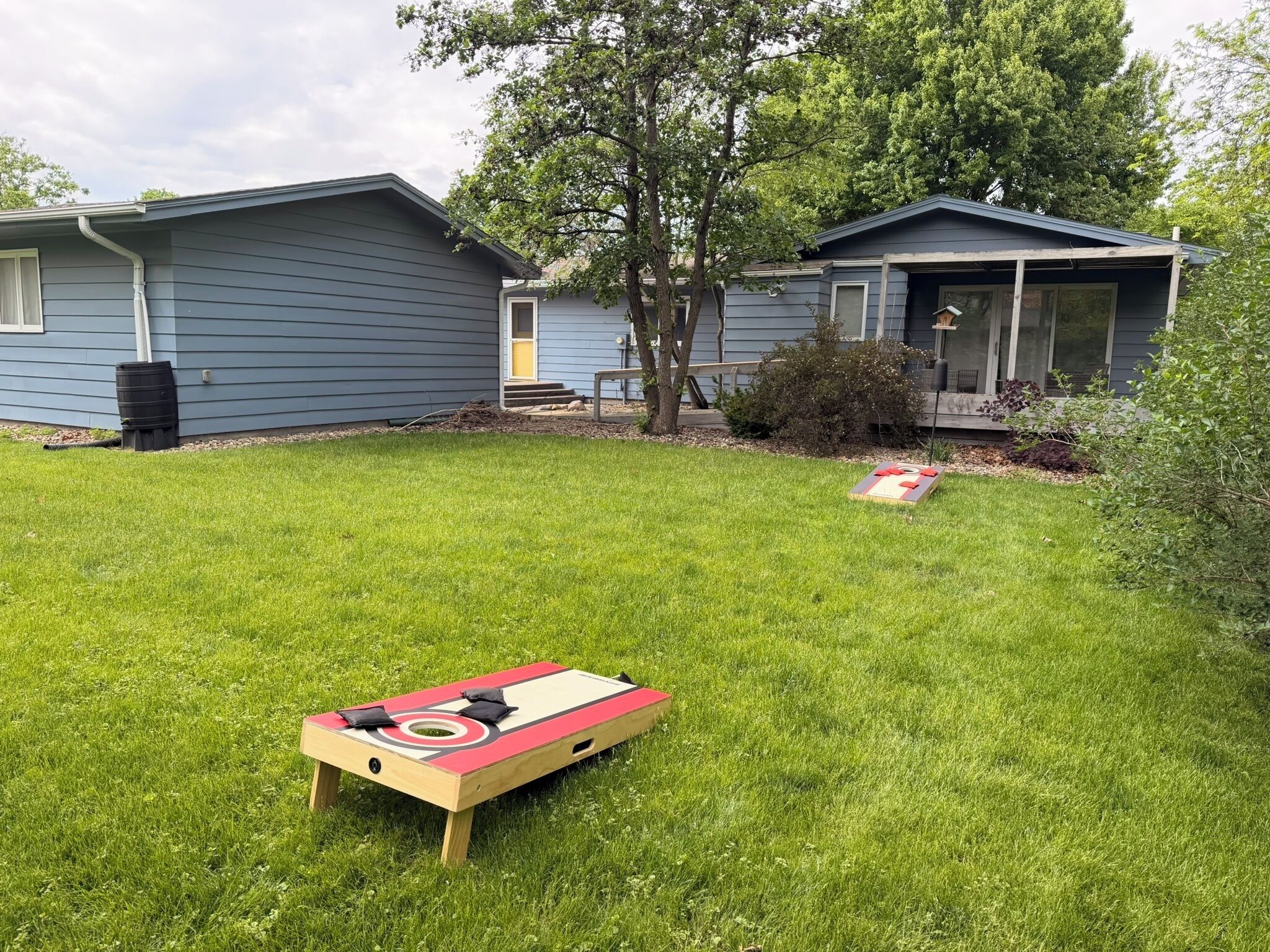 Ein Garten mit Shuffleboardtisch, einem Baum und zwei Häusern.
