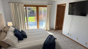 A bedroom with a bed, curtains, a TV, and a view of the outdoors. - Sleeps 10 - 5BR - Minutes to Campus - Next to Park, Golf, Shopping (Ames)
