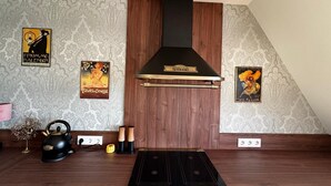 Una cocina con estufa moderna, extractor de aire negro y carteles antiguos en la pared.
