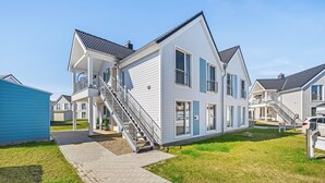 A two-story house with a balcony, a staircase, and a driveway. - Havhus - Sauna, fireplace, washing machine, electric vehicle charging station (Olpenitz)