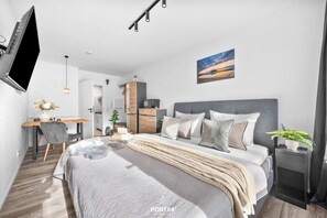 Un dormitorio moderno con cama, mesita de noche y zona de escritorio.