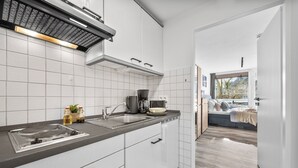 Une cuisine moderne avec des meubles blancs, un plan de travail noir et une vue sur un balcon.