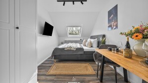 Une chambre à coucher moderne, équipée d’un lit, d’un bureau, d’une chaise, d’une fenêtre et d’un téléviseur fixé au mur.