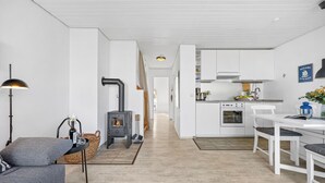 Ett modernt kök med vita skåp, en inbyggd ugn och en matplats med vita stolar.