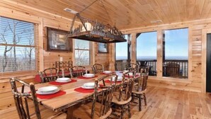 Ein Esszimmer aus Holz mit einem langen Tisch, gedeckt für sechs Personen, Holzstühlen und einem großen Fenster mit Aussicht.